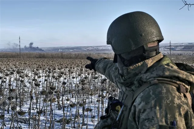 A Ukrainian soldier points at raising smoke on his position in the frontline near Soledar, Donetsk region, Ukraine, Wednesday, January 11, 2023. (Photo by Libkos/AP Photo)