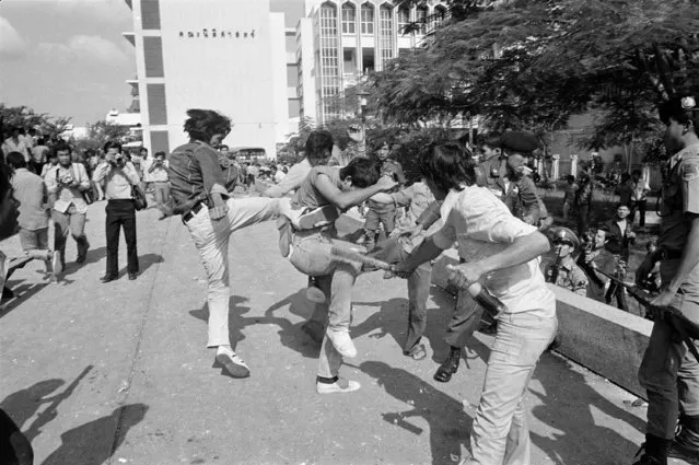 In this October 6, 1976 file photo right-wing Thai students kick and beat a leftist student who surrendered after a battle on the campus of Thammasat  University in Bangkok, Thailand. (Photo by Neal Ulevich/AP Photo)