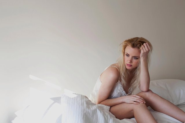 Upset young woman sitting on bed. (Photo by : Imagesourceprem/Getty Images)