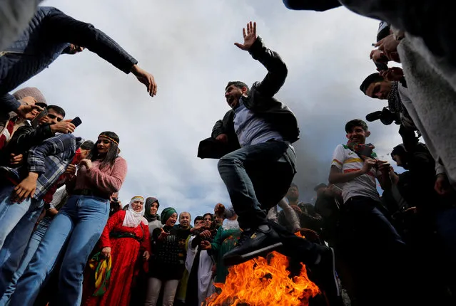 A man jumps over a bonfire during a gathering to celebrate Newroz, which marks the arrival of spring and the new year, in Istanbul, Turkey March 21, 2018. (Photo by Murad Sezer/Reuters)