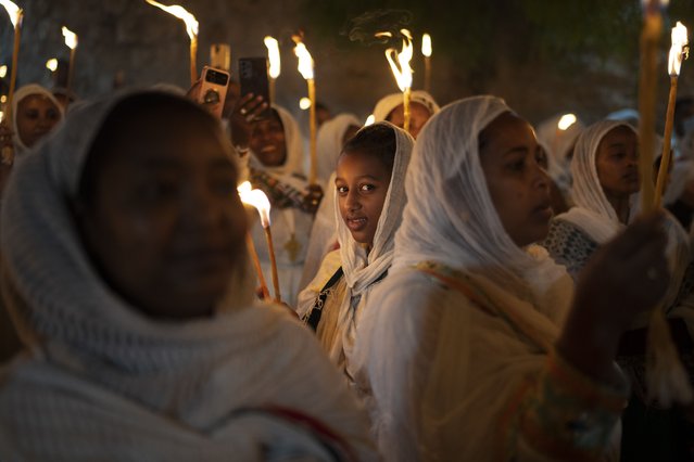 An Ethiopian Orthodox Christian pilgrim, looks at the camera as she holds a candle during the procession of the Holy Fire, at the Ethiopian monks' village Deir Al-Sultan, in the Old City of Jerusalem, Saturday, May 4, 2024. (Photo by Leo Correa/AP Photo)