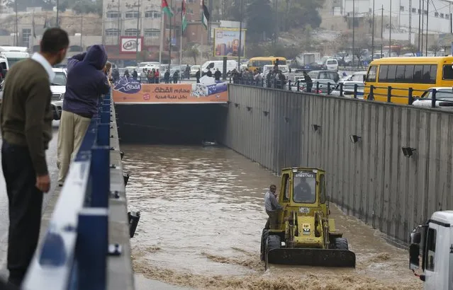 People look as workers on a loader attempt to clear floodwater from a tunnel in Amman, Jordan, November 5, 2015. Heavy rains caused the closure of main streets in the capital Amman and other cities, local media reported. (Photo by Muhammad Hamed/Reuters)
