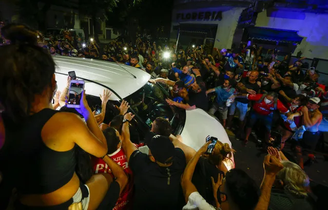 Soccer fans surround the hearse carrying the coffin of Diego Maradona to a funeral house in Buenos Aires, Argentina, Wednesday, November 25, 2020. The Argentine soccer great who was among the best players ever and who led his country to the 1986 World Cup title died from a heart attack at his home in Buenos Aires. He was 60. (Photo by Marcos Brindicci/AP Photo)