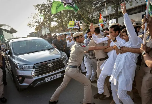 A police officer pushes away supporters of Rahul Gandhi, a senior leader of India's main opposition Congress party, as he leaves in a car from the New Delhi airport, after he appeared before a court in Surat in the western state of Gujarat, India on March 23, 2023. (Photo by Adnan Abidi/Reuters)