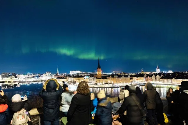 People watch northern lights, aurora borealis, in central Stockholm, on February 27, 2023. (Photo by Ali Lorestani/TT News Agency via AFP Photo)