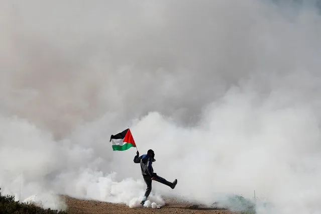 A Palestinian demonstrator reacts to tear gas fired by Israeli forces during a protest against Jewish settlements, in Beit Dajan in the Israeli-occupied West Bank on December 18, 2020. (Photo by Mohamad Torokman/Reuters)