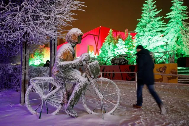 A man walks past a snow-covered installation depicting a bicyclist in Stavropol, Russia on December 23, 2020. (Photo by Eduard Korniyenko/Reuters)