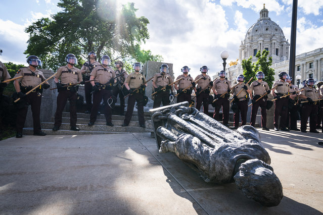Minnesota State Troopers surrounded the statue of Christopher Columbus after it was toppled in front of the Minnesota State Capitol, Wednesday, June 10, 2020, in St. Paul, Minn. The statue was later towed away. (Photo by Leila Navidi/Star Tribune via AP Photo)