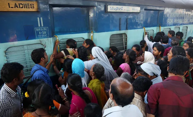 Indian women stand in front of a train door that was closed by a security officer asking them to first form a queue to enter, as people crowd a railway platform in Hyderabad, India, Saturday, January 10, 2015. Railway platforms and trains were overcrowded Saturday as most people travelled to their hometowns to celebrate the Hindu festival of Makar Sankranti that falls on Jan. 14. (Photo by Mahesh Kumar A./AP Photo)