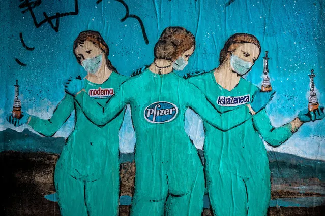 “The Three Vaccines”, a graffiti by Italian urban artist “TVBoy”, Salvatore Benintende, depicting three figures holding covid-vaccines from “moderna”, “Pfizer” and “AstraZeneca” in mid of the ongoing coronavirus disease is based on 15th-century oil painting “Three Graces” by Italian painter Raphael in Barcelona, Spain on January 19, 2021. (Photo by Matthias Oesterle/ZUMA Wire/Rex Features/Shutterstock)