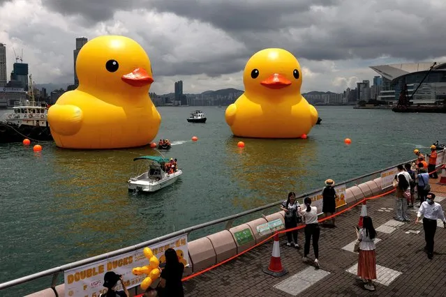 People take photos of an art installation, dubbed “Double Ducks” by Dutch artist Florentijn Hofman, seen at Victoria Harbour, in Hong Kong, China on June 9, 2023. (Photo by Tyrone Siu/Reuters)