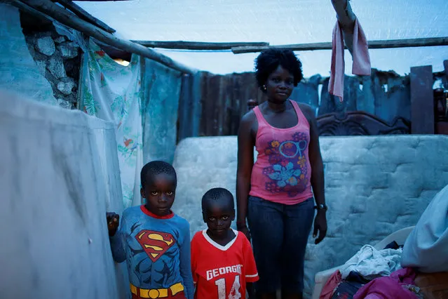 Marie Ange St Juste (R), 29, poses for a photograph with her sons, Kensley, 7 (L), and Peterley, 5, in their destroyed house after Hurricane Matthew hit Jeremie, Haiti, October 17, 2016. Haiti had been hit so hard by Hurricane Matthew, the fiercest Caribbean storm in nearly a decade, that people considered themselves lucky to be alive. Villages making contact with the outside in early October, days after the cyclone ripped through the impoverished nation's picturesque western peninsula, like Jeremie, were in ruins. “My house was totally destroyed during the storm”, said 29-year-old mother Marie Ange St Juste. “I lost everything, but I was lucky that none of my children died. Now my situation is very bad, we need help”. The death toll rose to more than 1,000 people. One of Matthew's worst repercussions was the outbreak of cholera. Many people flooded hospital units for treatment. (Photo by Carlos Garcia Rawlins/Reuters)