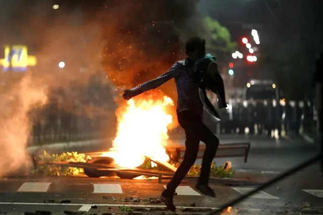A demonstrator runs during a protest against racism, after Joao Alberto Silveira Freitas was beaten to death by security guards at a Carrefour supermarket in Porto Alegre, Brazil, November 23, 2020. In a video circulated widely on social media, two security guards were shown punching and pinning the 40-year-old Black man to the ground. Activists have organized demonstrations outside of Carrefour stores since Friday. The two men have been arrested and Carrefour Brasil said it has terminated its contract with the security firm. (Photo by Diego Vara/Reuters)