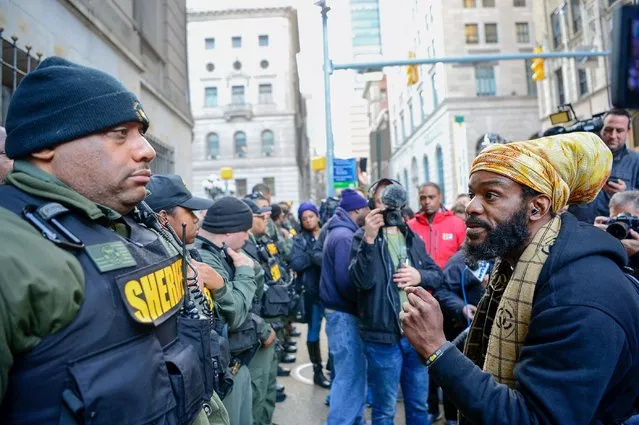 A protestor confronts deputies from Baltimore City Sheriff's Office outside the courthouse in Baltimore, December 16, 2015. A Maryland judge declared a mistrial on Wednesday in the trial of the first of six Baltimore police officers charged in the death of Freddie Gray, whose killing sparked riots and arson in the city in April. The jury had deliberated for 16 hours on whether the officer. (Photo by Bryan Woolsto/Reuters)