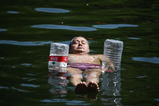 A man uses water bottles for flotation as he cools off in a canal in Beijing on June 22, 2023. Swathes of northern China sweltered in 40-degree heat on June 22, weather data showed, as parts of Beijing and the nearby megacity of Tianjin recorded their highest temperatures for years. (Photo by Greg Baker/AFP Photo)