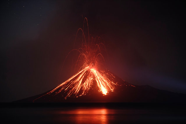 Lava streams down from Anak Krakatau (Child of Krakatoa) volcano during an eruption as seen from Rakata island in South Lampung on July 19, 2018. An Indonesian volcano known as the “child” of the legendary Krakatoa erupted on July 19, spewing a plume of ash high into the sky as molten lava streamed down from its summit. Anak Krakatau – a small volcanic island that emerged from the ocean a half century after Krakatoa's deadly 1883 eruption – has rumbled back to life in recent weeks, spitting flaming rocks and ash from its crater. (Photo by Ferdi Awed/AFP Photo)