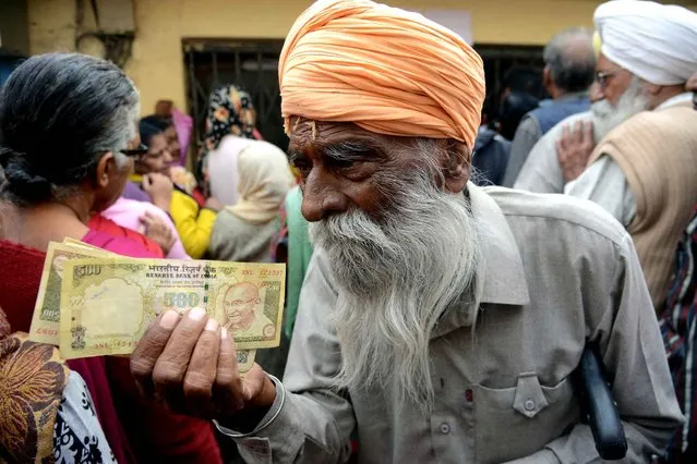 Indian senior citizens gather outside a bank as they wait to deposit and exchange 500 and 1000 rupee notes in Amritsar on November 19, 2016. Long queues formed outside banks in India since the government' s shock decision to withdraw the two largest denomination notes from circulation India' s government asked its citizens to put up with what it called the “short- term inconvenience” when it announced the move to withdraw 85 percent of currency in circulation in a bid to tackle widespread tax evasion. (Photo by Narinder Nanu/AFP Photo)