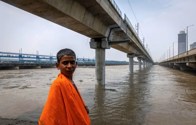 A boy stands on the bank of the river Yamuna, overflowing due to heavy monsoon rains, in New Delhi, India on July 14, 2023. (Photo by Adnan Abidi/Reuters)