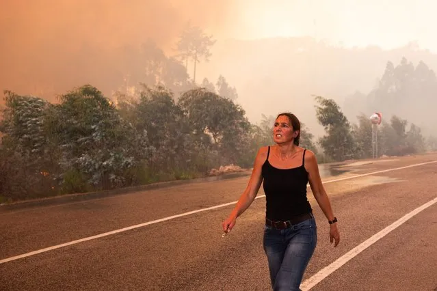 A woman walks on the A1 highway in the locality of Cardosos as a forest fire caused the motorway to be cut off this afternoon, Leiria, Portugal, 7 August 2023. (Photo by Paulo Cunha/EPA)