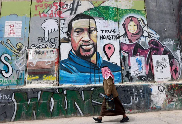 A man walks past a mural showing the face of George Floyd, an unarmed handcuffed black man who died after a white policeman knelt on his neck during an arrest in the US, painted on a section of Israel's controversial separation barrier in the city of Bethlehem in the occupied West Bank on March 31, 2021. The teenager who took the viral video of George Floyd's death said on March 30, at the trial of the white police officer charged with killing the 46-year-old Black man that she knew at the time “it wasn't right”. Darnella Frazier, 18, was among the witnesses who gave emotional testimony on Tuesday at the high-profile trial of former Minneapolis police officer Derek Chauvin. Chauvin, 45, is charged with murder and manslaughter for his role in Floyd's May 25, 2020 death, which was captured on video by Frazier and seen by millions, sparking anti-racism protests around the globe. (Photo by Emmanuel Dunand/AFP Photo)