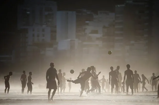 Brazilians play altinha, a spin-off of soccer played on the beach, as others gather on Ipanema Beach, April 21, 2014, in Rio de Janeiro, Brazil. Altinha is Portuguese for “a little higher” and involves players attempting to keep the ball in the air without using their hands. (Photo by Mario Tama/Getty Images)