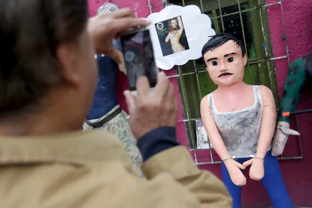 A pedestrian takes a photo with his cellphone of a pinata depicting the drug lord Joaquin "El Chapo" Guzman outside a workshop in Reynosa, in Tamaulipas state, Mexico, January 13, 2016. (Photo by Daniel Becerril/Reuters)