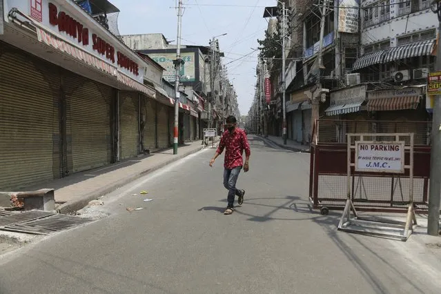 A man walks past closed shops in a market during a lockdown imposed to curb the spread of the coronavirus in Jammu, India, Friday, May 7, 2021. (Photo by Channi Anand/AP Photo)
