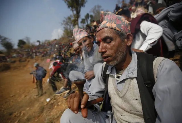 A villager smokes tobacco during the bullfight organized to mark the Maghesangranti festival at Talukachandani village in Nuwakot district near Kathmandu, Nepal January 15, 2016. (Photo by Navesh Chitrakar/Reuters)