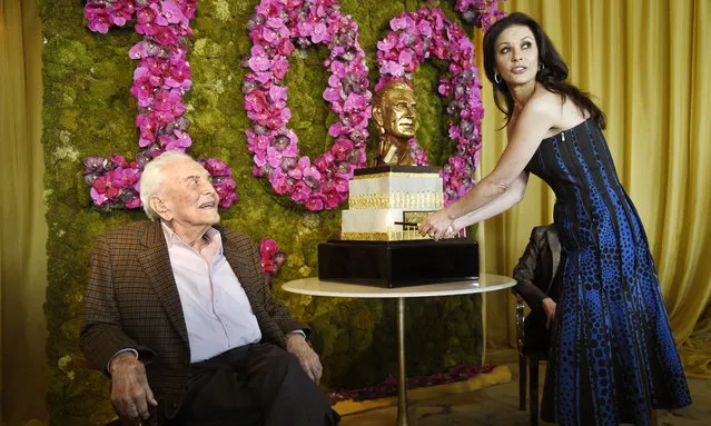 Actor Kirk Douglas, left, looks on as his daughter-in-law Catherine Zeta-Jones lights the candles on his birthday cake during his 100th birthday party at the Beverly Hills Hotel on Friday, December 9. 2016, in Beverly Hills, Calif. (Photo by Chris Pizzello/Invision/AP Photo)