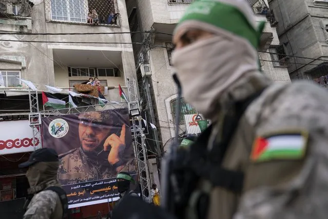 Residents watch from balconies as Hamas militants parade through the streets for Bassem Issa, a top Hamas' commander, who was killed by Israeli Defense Force military actions prior to a cease-fire reached after an 11-day war between Gaza's Hamas rulers and Israel, in Gaza City, Saturday, May 22, 2021. (Photo by John Minchillo/AP Photo)