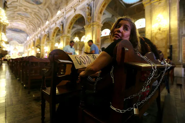 Relatives of victims of human rights abuses during the former dictatorship of Augusto Pinochet chain themselves to pews at the Cathedral of Santiago to protest against a mass taking place in the special prison for human right abusers called “Punta Peuco”, acccording to local media, in Santiago, Chile December 22, 2016. (Photo by Ivan Alvarado/Reuters)