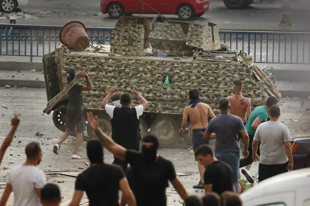 Supporters of Prime Minister-designate Saad Hariri who stepped down on Thursday, throw stones against an armored personnel carrier of the Lebanese army, in Beirut, Lebanon, Thursday, July 15, 2021. (Photo by Hussein Malla/AP Photo)