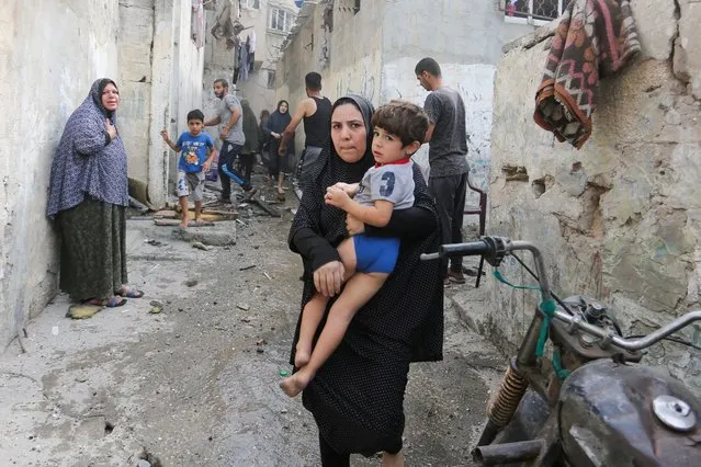A woman holds a child as Palestinians are evacuated at the site of an Israeli strike on a house, in Rafah in the southern Gaza Strip on November 11, 2023. (Photo by Hatem Khaled/Reuters)