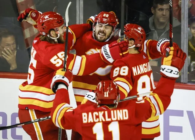 Calgary Flames defenseman MacKenzie Weegar, center, celebrates his goal with teammates in overtime of an NHL hockey game against the Vegas Golden Knights in Calgary, Alberta, Monday, November 27, 2023. (Photo by Jeff McIntosh/The Canadian Press via AP Photo)