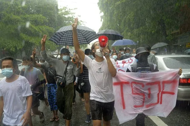 Anti-coup protesters flash the three-finger salute and chant slogans during a demonstration against the military coup in the rain at Pabedan township in Yangon, Myanmar, Friday, April 30, 2021. (Photo by Vincent Thian/AP Photo)
