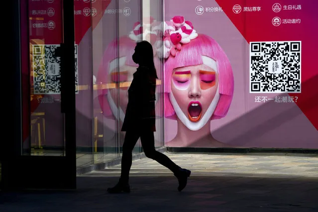 A woman walks past an advertisement at the entrance of a clothing store in Beijing on January 13, 2017. Chinese exports fell more than expected in December, data showed on January 13, deepening concerns about the trade outlook for the world's number-two economy as Donald Trump prepares to take office. (Photo by Wang Zhao/AFP Photo)