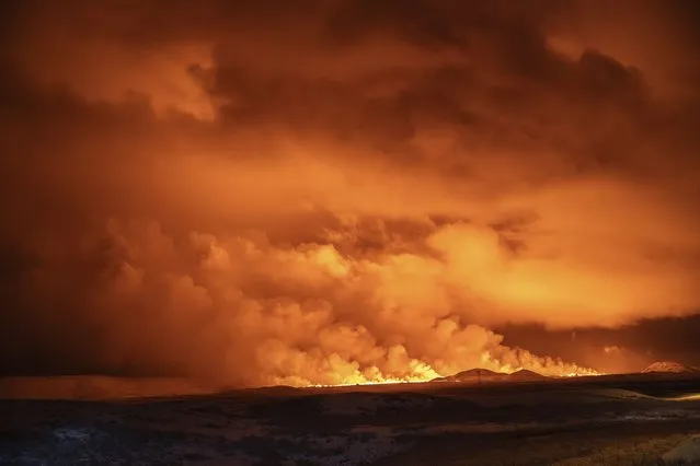 The night sky is illuminated caused by the eruption of a volcano in Grindavik on Iceland's Reykjanes Peninsula, Monday, December 18, 2023. (Photo by Marco Di Marco/AP Photo)