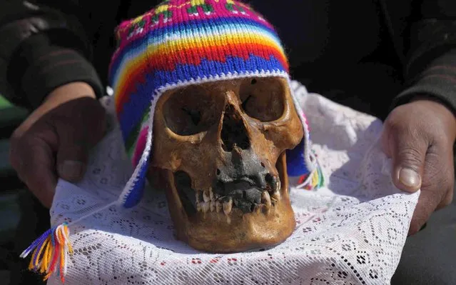 A person carries a human skull for it to be blessed by a priest during the annual “Natitas” festival, a tradition marking the end of the Catholic All Saints holiday, at the General Cemetery in La Paz, Bolivia, Tuesday, November 8, 2022. The “Natitas”, which means “without a nose” in the Indigenous Aymara language, are cared for and decorated by those who use them as amulets for protection. (Photo by Juan Karita/AP Photo)
