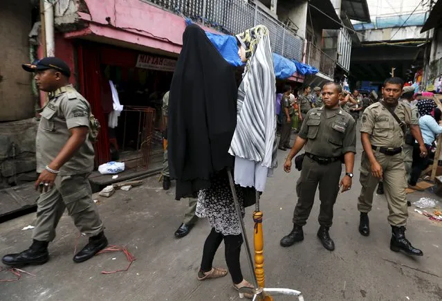 A street vendor saves her belongings as Civil Service policemen look on during a sweep operation against illegal steet vendors causing traffic congestion at Tanah Abang market in Jakarta, April 7, 2015. (Photo by Reuters/Beawiharta)