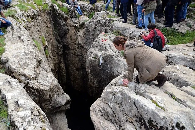 A woman leans to peek into a chasm as Armenian people gather during a commemoration ceremony at a site called “Dudan” near Diyarbakir, and believed to be a mass grave of the Armenian Genocide, on April 22, 2015. Armenians prepare to commemorate a hundred years since a genocide wiped out up to 1.5 million of their kin as a fierce dispute still rages with Turkey over one of the greatest crimes of the 20th century. (Photo by Ilyas Akengin/AFP Photo)