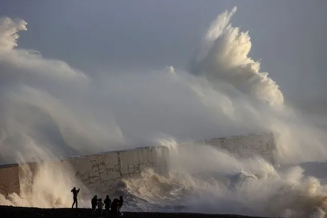 A person takes a photograph as waves break against the breakwater in Newhaven on January 2, 2024, as Storm Henk brought strong winds and heavy rain across much of southern England. (Photo by Adrian Dennis/AFP Photo)