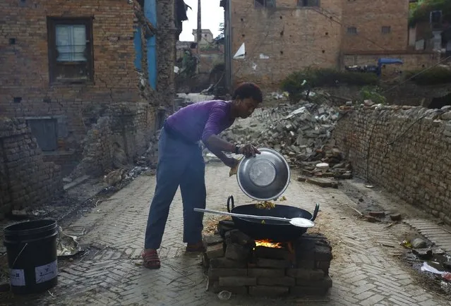 A man cooks potatoes near collapsed houses along the streets of Bhaktapur after an earthquake in Nepal April 27, 2015. (Photo by Navesh Chitrakar/Reuters)