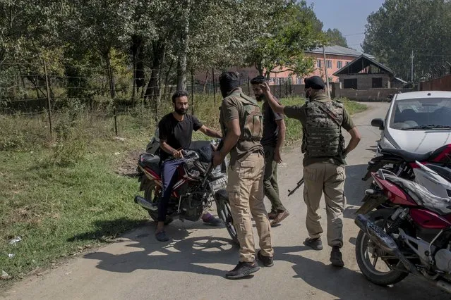 Indian policemen chase away Kashmiri motorcyclists as they cordon off the area outside a government school where two teachers were shot dead by assailants in the outskirts of Srinagar, Indian controlled Kashmir, Thursday, October 7, 2021. Authorities blamed militants fighting against Indian rule for the attack. Thursday’s incident marks the seventh targeted killings in six days. (Photo by Dar Yasin/AP Photo)