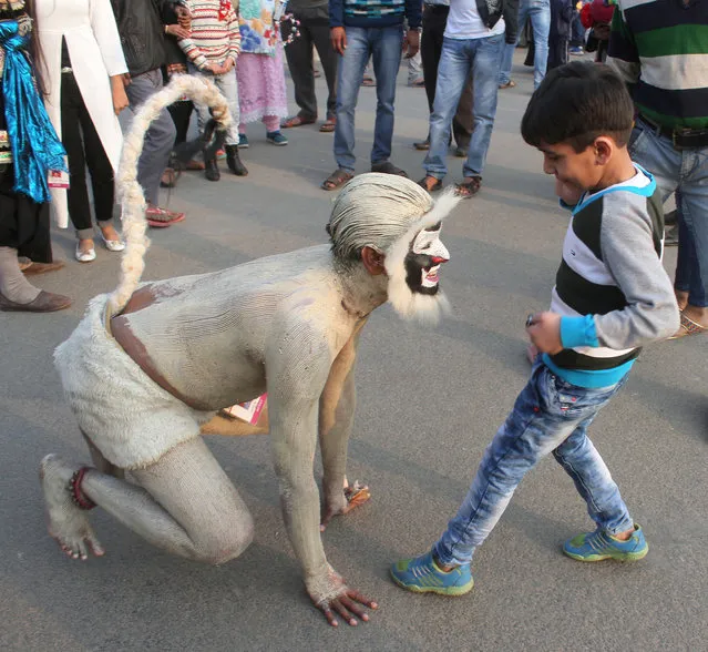 An artist dressed as monkey plays with a boy at Bharat Parv event at Red Fort on January 30, 2017 in New Delhi, India. The highlights of event include display of the Republic Day Parade Tableaux, performances by the Armed Forces Bands, a multi-cuisine food court, crafts mela and cultural performances from different regions of the country. (Photo by Zuhaib Mohammad/Hindustan Times via Getty Images)