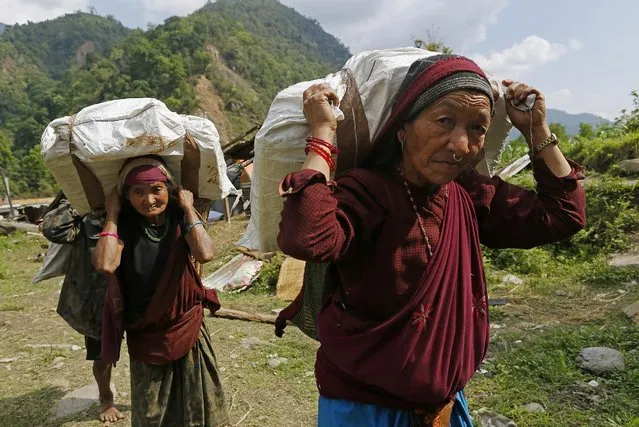 Elderly villagers start their 20km (12 mile) hike back up to their mountain home with international relief aid they received in the damaged village of Balua, near the epicenter of Saturday's massive earthquake, in the Gorkha District of Nepal, Thursday, April 30, 2015. (Photo by Wally Santana/AP Photo)