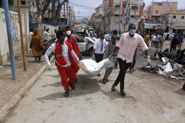 Medical personnel carry a body after a car bomb attack at a Presidential Palace checkpoint in Mogadishu, Somalia, Saturday September 25, 2021. Police said a vehicle laden with explosives rammed into cars and trucks at a checkpoint leading to the entrance of the Presidential Palace, killing at least eight people. (Photo by Farah Abdi Warsameh/AP Photo)