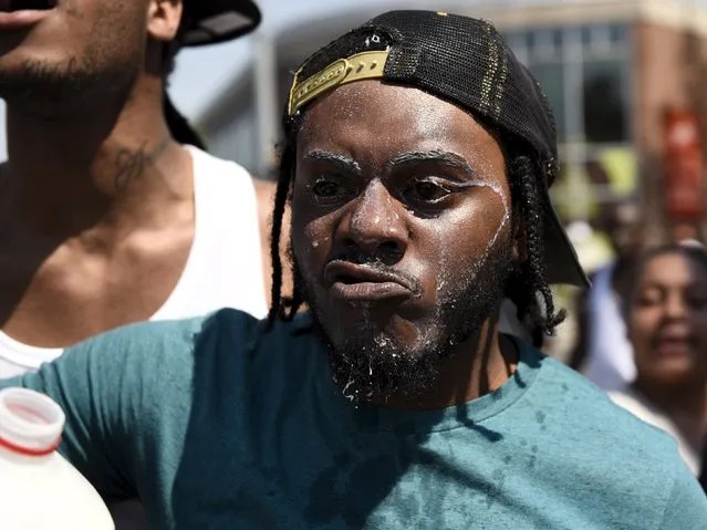 A man with milk on his face used to treat the effects of pepper spray confronts law enforcement officers at the intersection of North and Pennsylvania Avenues after officers sprayed a crowd reacting to an incident where a firearm went off during an arrest in West Baltimore, May 4, 2015. (Photo by Sait Serkan Gurbuz/Reuters)