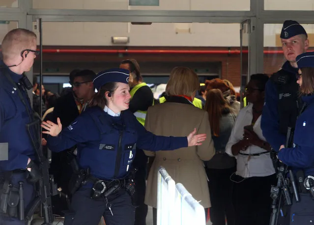 A police officer gestures outside a gym where passengers took shelter after the explosions, near  the  Zaventem Airport in Brussels, Tuesday, March 22, 2016. Bombs struck the Brussels airport and one of the city's metro stations Tuesday, killing and wounding dozens of people, as a European capital was again locked down amid heightened security threats. (Photo by Michel Spingler/AP Photo)