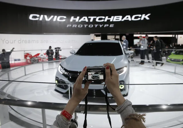 A woman takes a photo of the Honda Civic Hatchback Prototype vehicle during the media preview of the 2016 New York International Auto Show in Manhattan, New York on March 24, 2016. (Photo by Brendan McDermid/Reuters)