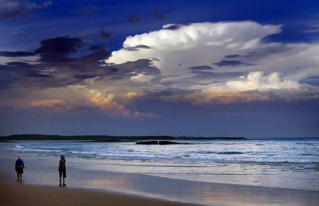 Storm clouds and dust can be seen in the sky above as people walk at dusk along Mollymook Beach, south of Sydney March 5, 2014. (Photo by David Gray/Reuters)